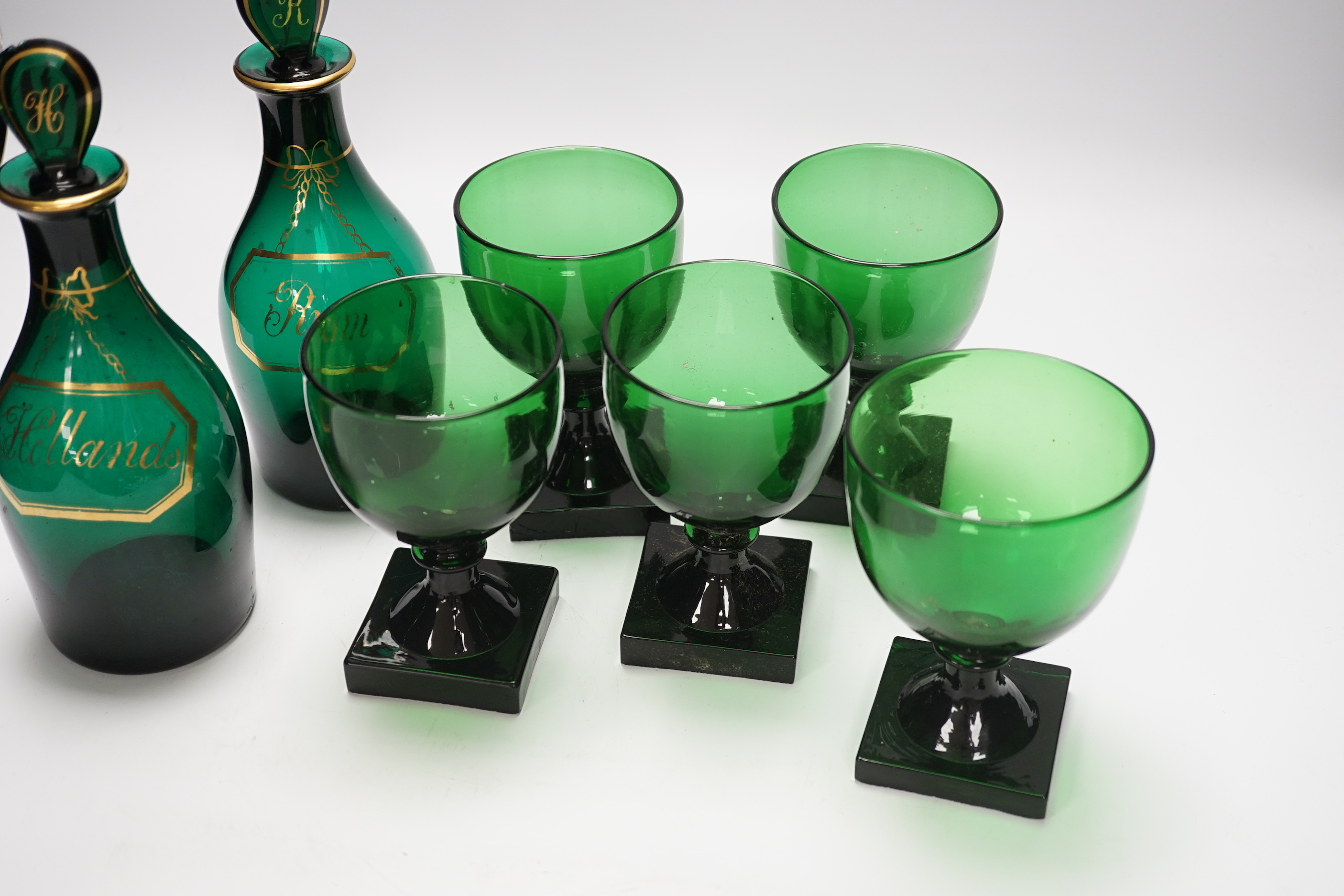 A pair of small Bristol green decanters, Rum and Hollands, c.1800 and five 19th century green glass rummers, with lemon squeezer bases, decanters 22cm high